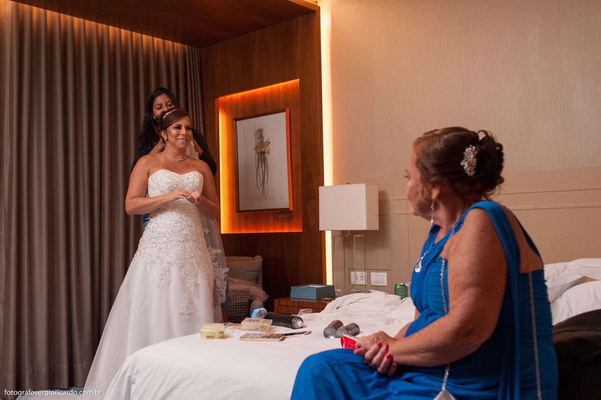 foto dos preparativos da noiva com maquiadora e mão em suite do hotel hilton barra