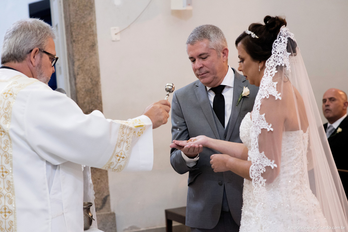 fotografia do casal de noivos recebendo a benção das alianças na igreja nossa senhora do loreto durante o casamento