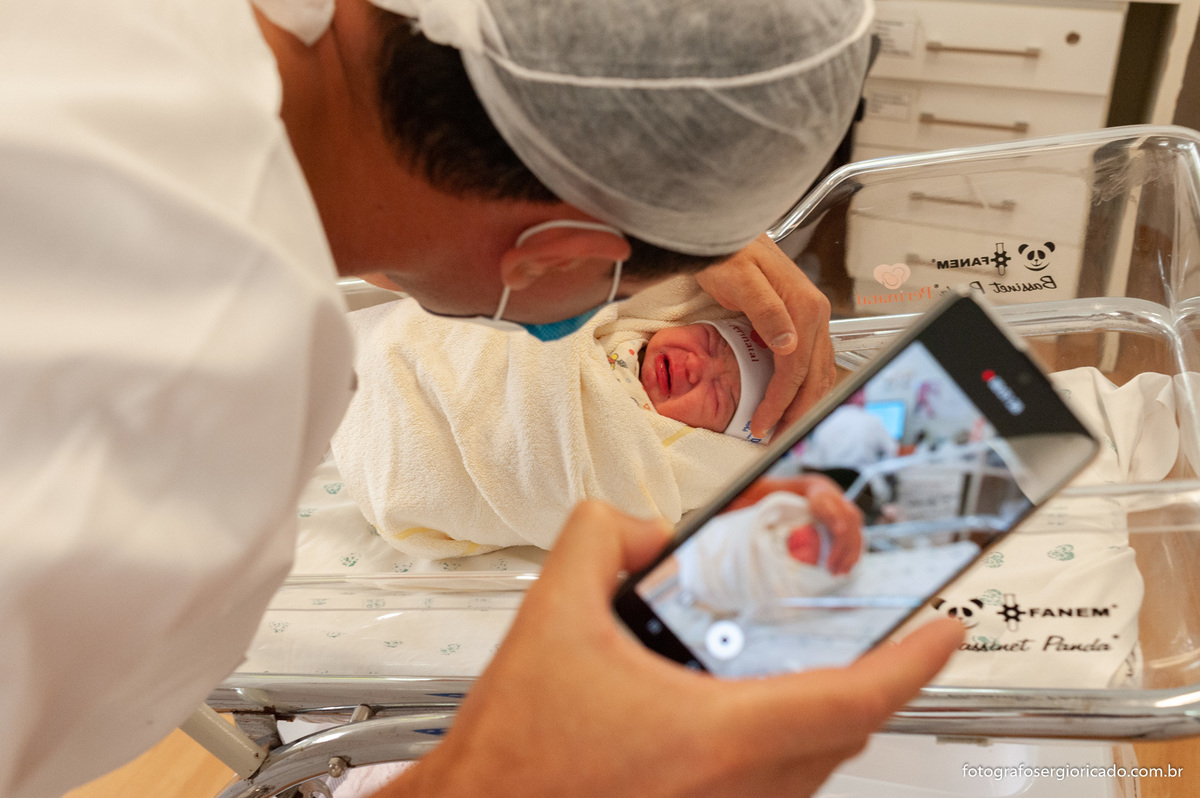 Fotografia do pai com a filha recém-nascida no berçário da Perinatal da Barra no Rio de Janeiro