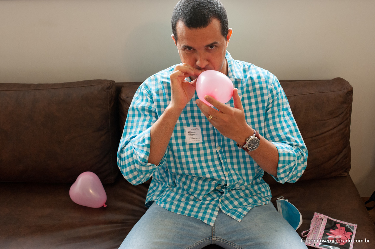 Pai enchendo bolas de gás para decorar o quarto para a chegada da filha na Perinatal Barra no Rio de Janeiro