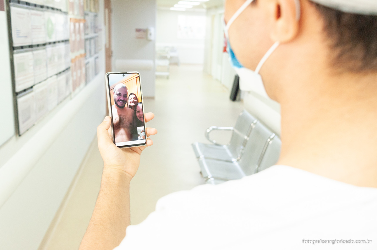 Pai recebendo mensagem no celular e aguardando para entrar na sala de parto na Perinatal da Barra 