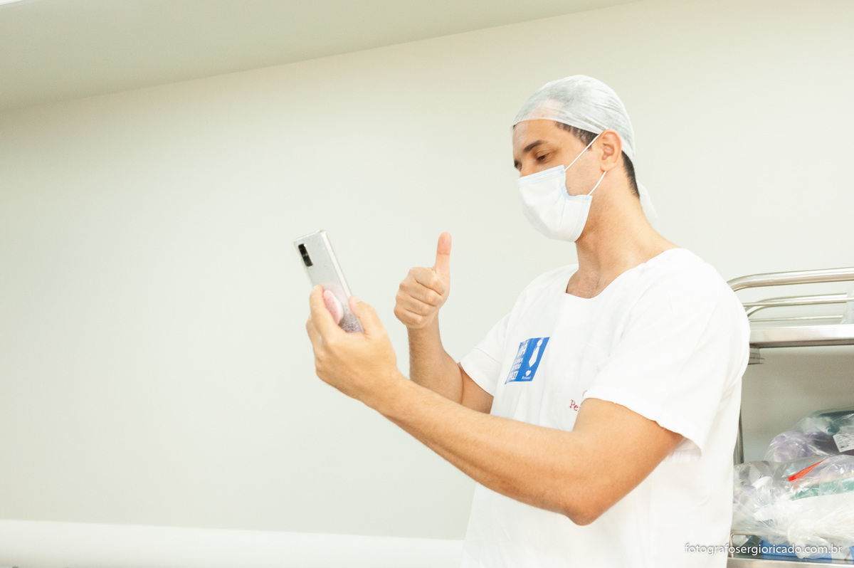 Pai recebendo mensagem no celular e aguardando para entrar na sala de parto na Perinatal da Barra 