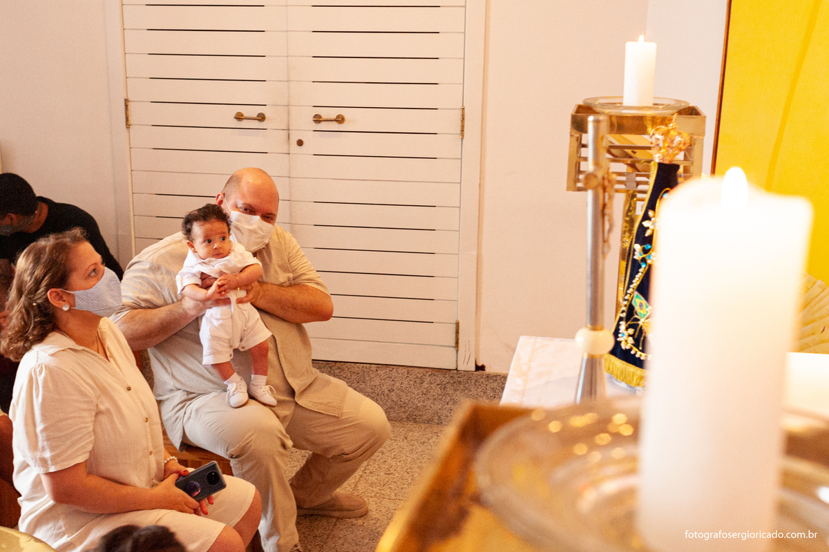Fotografia dos pais com criança na cerimônia de batismo na Capela de Nossa Senhora Aparecida no Cristo Redentor localizado no Morro do Corcovado no Rio de Janeiro