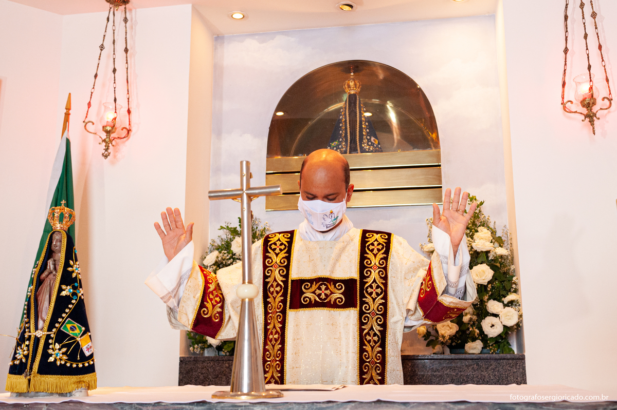 Fotografia do padre realizando cerimônia de batismo na Capela de Nossa Senhora Aparecida no Cristo Redentor localizado no Morro do Corcovado no Rio de Janeiro