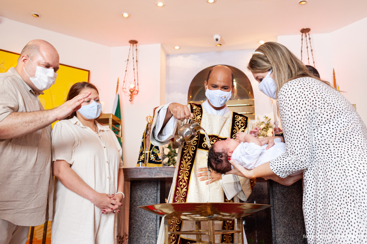 Fotografia dos pais e madrinha com criança recebendo o batismo na Capela de Nossa Senhora Aparecida no Cristo Redentor localizado no Morro do Corcovado no Rio de Janeiro