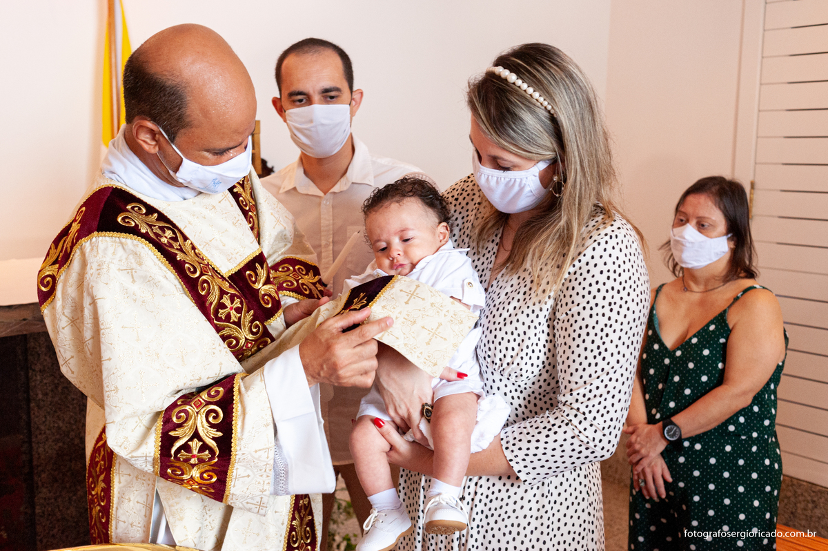 Fotografia dos padrinhos e convidados com criança recebendo o batismo na Capela de Nossa Senhora Aparecida no Cristo Redentor localizado no Morro do Corcovado no Rio de Janeiro
