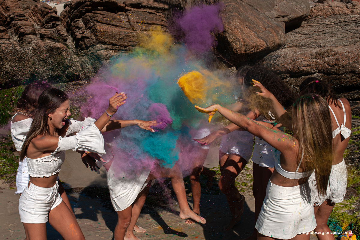 foto de ensaio de 15 anos com as amigas brincando com pó colorido na praia da joatinga no rio de janeiro
