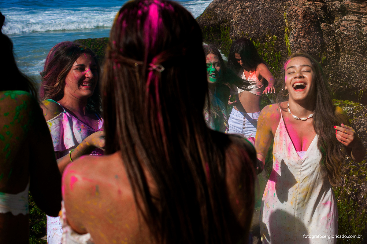 foto de ensaio de 15 anos com as amigas brincando com pó colorido na praia da joatinga no rio de janeiro