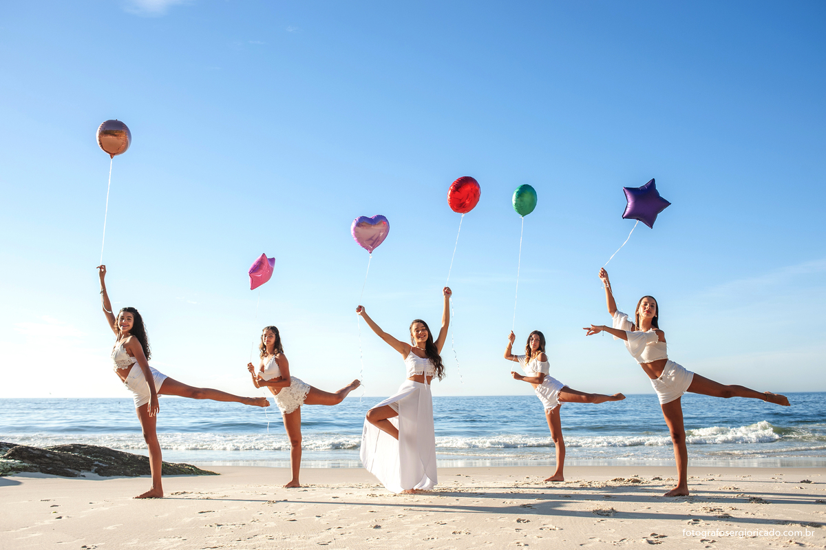 fotografia de ensaio de 15 anos com amigas segurando balões de gás coloridos na praia da joatinga no rio de janeiro