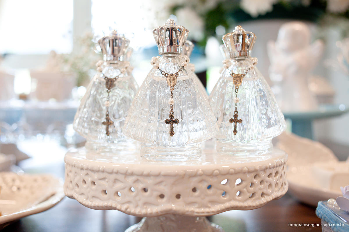 Fotografia de lembranças em forma de nossa senhora no batizado de menino feita por Brenda Rebelo em tom azul claro na Barra da Tijuca no Rio de Janeiro