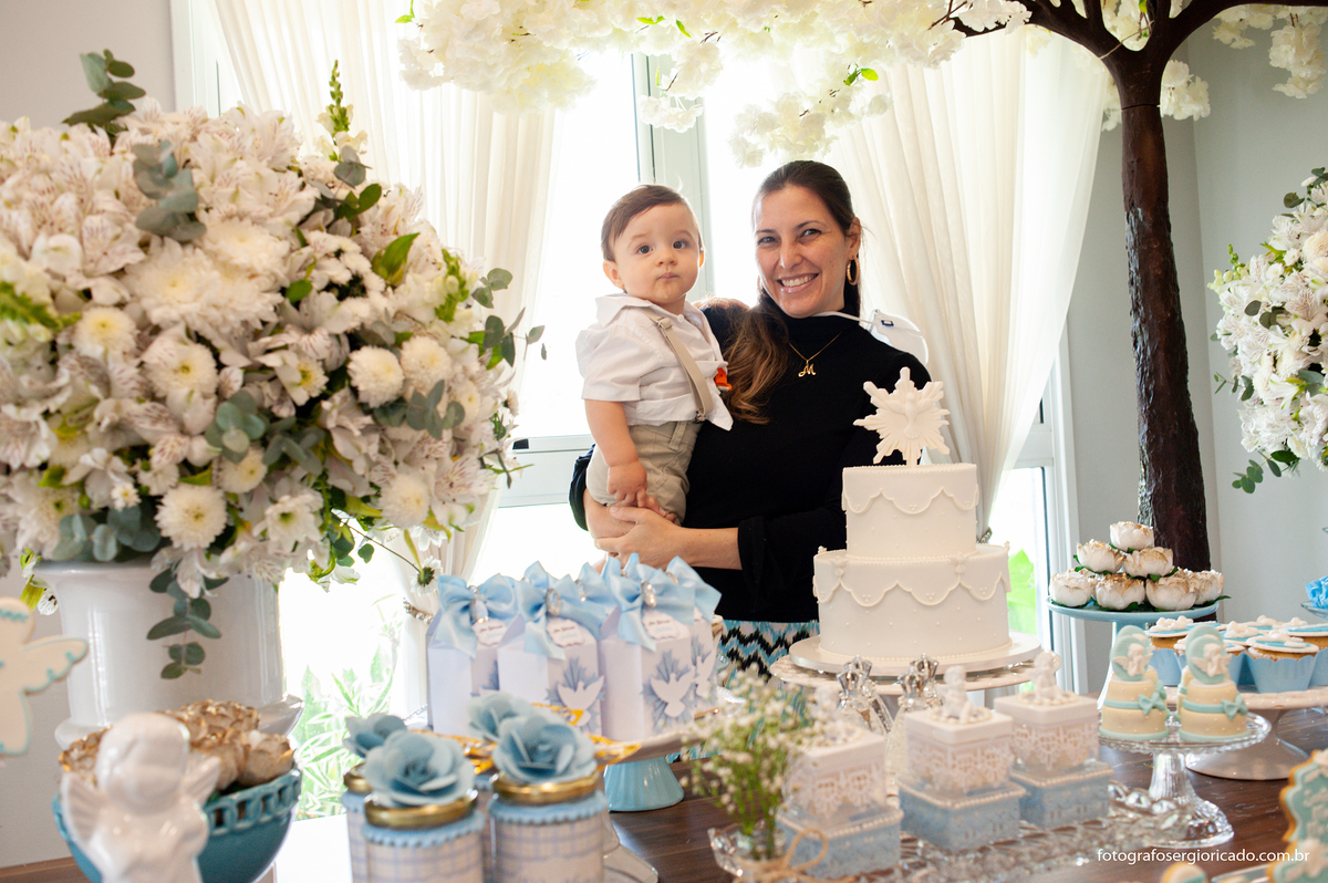 Fotografia da tia com o sobrinho no colo na mesa decorada em festa de batismo na Barra da Tijuca no Rio de Janeiro 