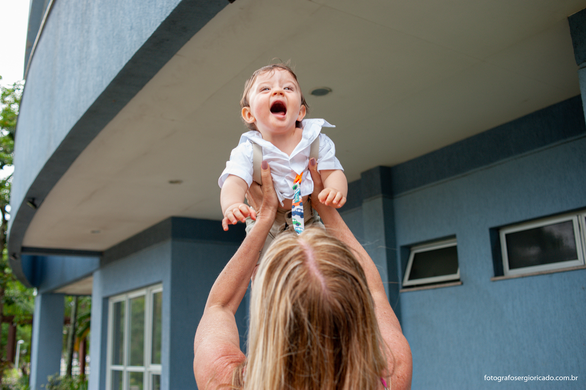 Fotografia de criança com a madrinha no jardim em festa de batismo na Barra da Tijuca no Rio de Janeiro 