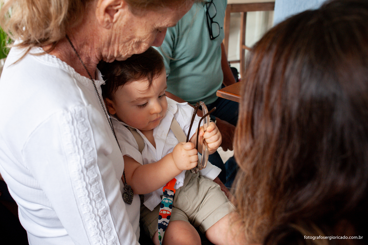 Fotografia da avó brincando com neto no colo durante almoço em festa de batismo na Barra da Tijuca no Rio de Janeiro 
