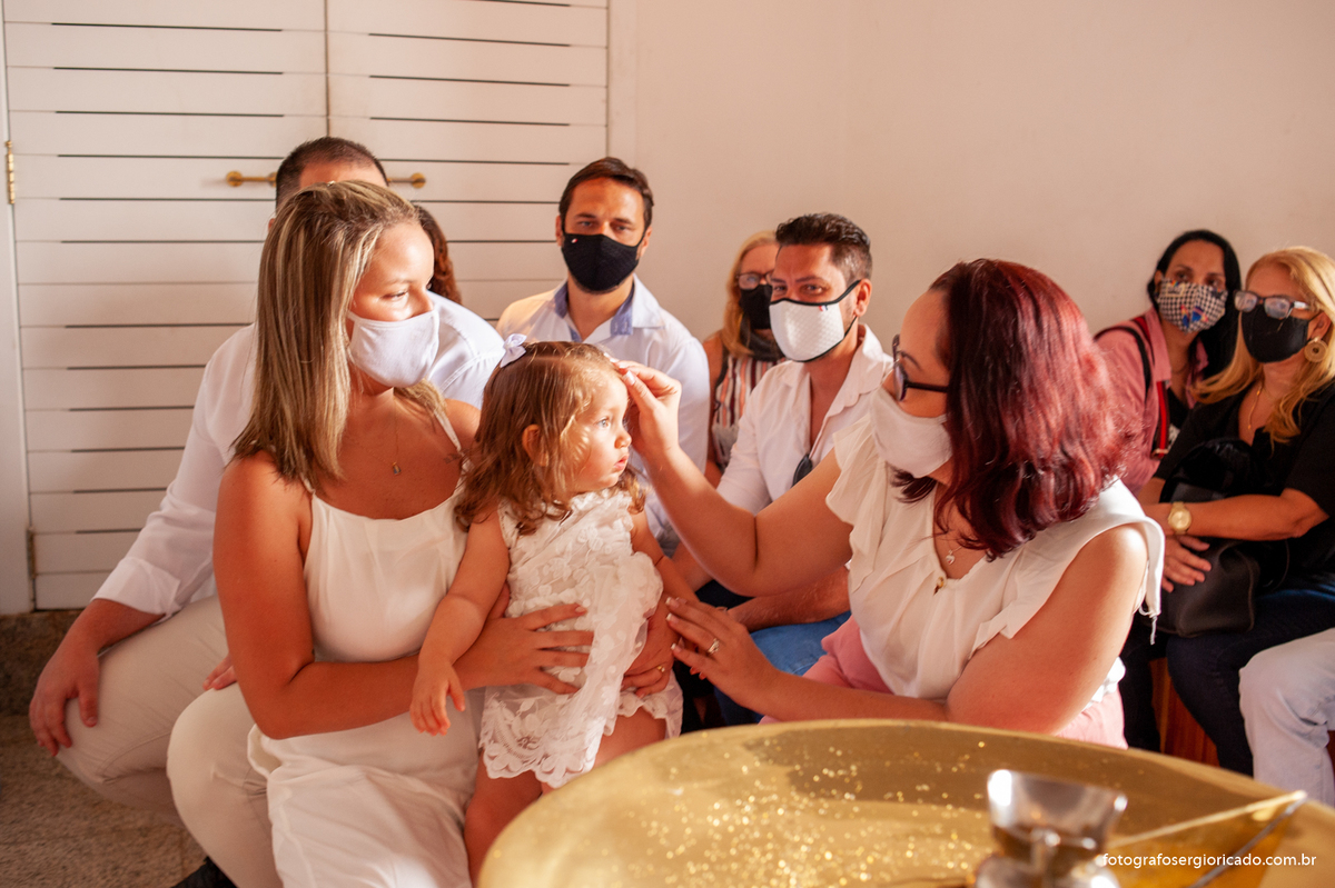 Fotografia da madrinha com criança na cerimônia de batismo na Capela de Nossa Senhora Aparecida no Cristo Redentor localizado no Morro do Corcovado no Rio de Janeiro