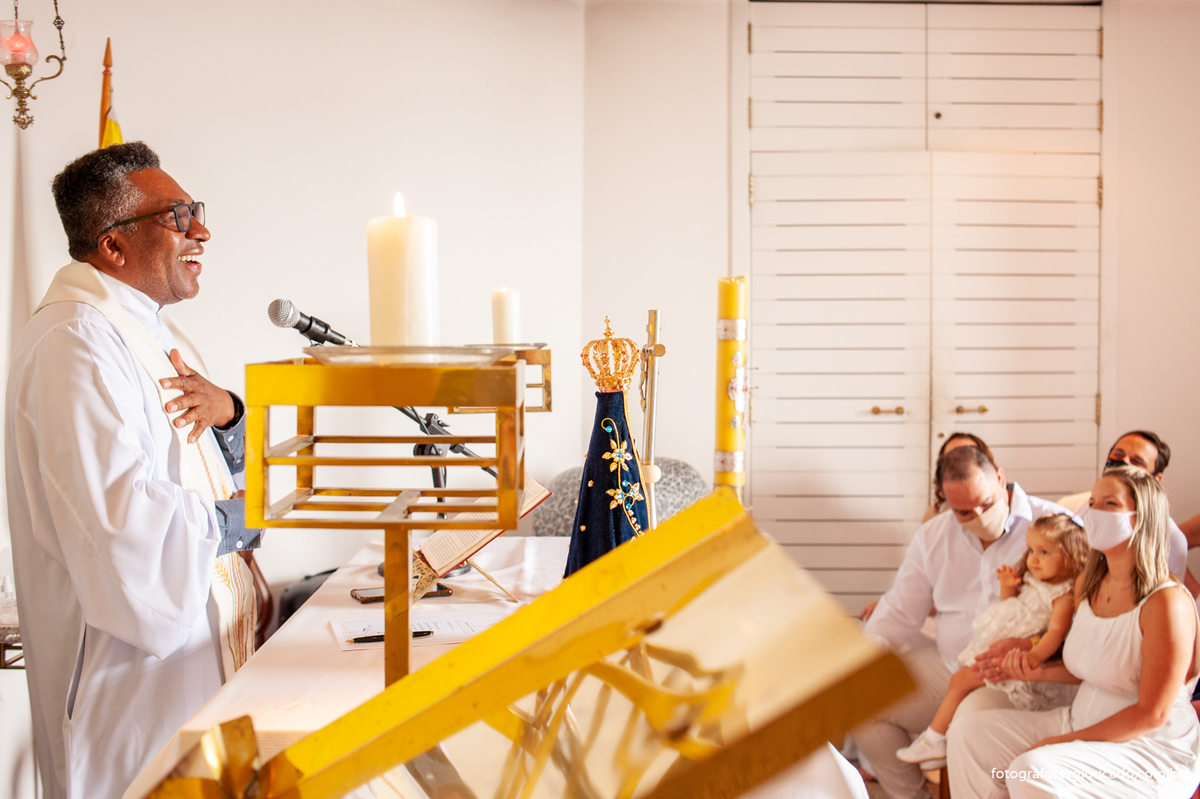 Foto dos pais com o padre realizando cerimônia de batismo na Capela de Nossa Senhora Aparecida no Cristo Redentor localizado no Morro do Corcovado no Rio de Janeiro