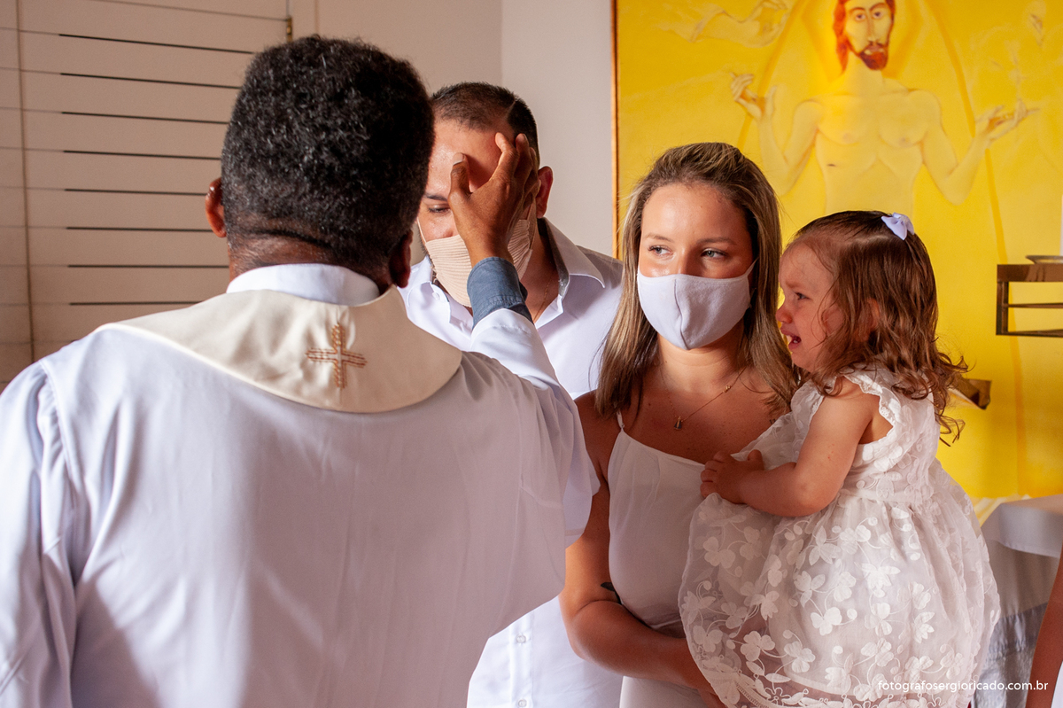 Foto dos pais com o padre realizando cerimônia de batismo na Capela de Nossa Senhora Aparecida no Cristo Redentor localizado no Morro do Corcovado no Rio de Janeiro