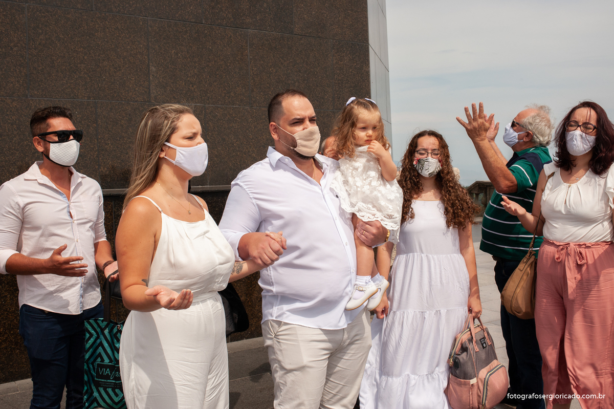 Imagem dos pais e padrinhos rezando pai nosso com o padre durante cerimônia de batismo na área externa da Capela de Nossa Senhora Aparecida no Cristo Redentor localizado no Morro do Corcovado no Rio de Janeiro