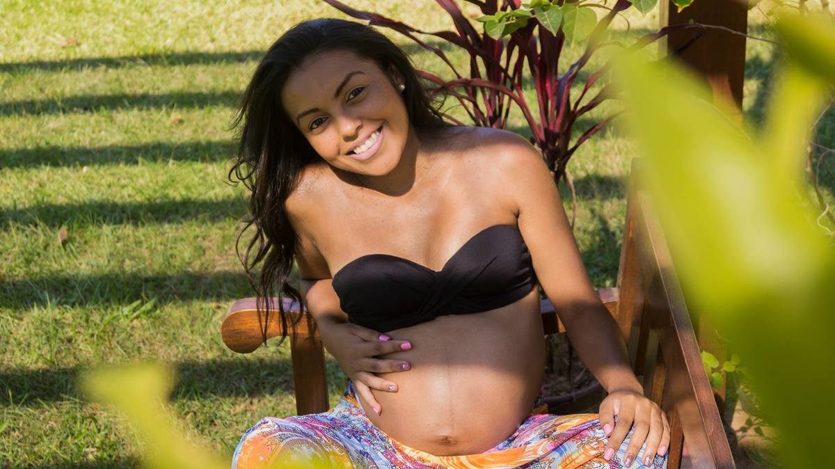Gestante sentada no banco sorri para a foto