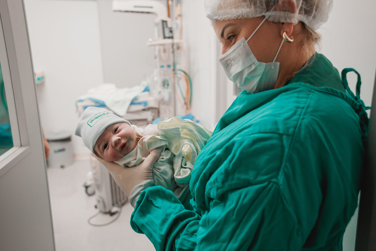 pediatra segurando bebê recém nascido