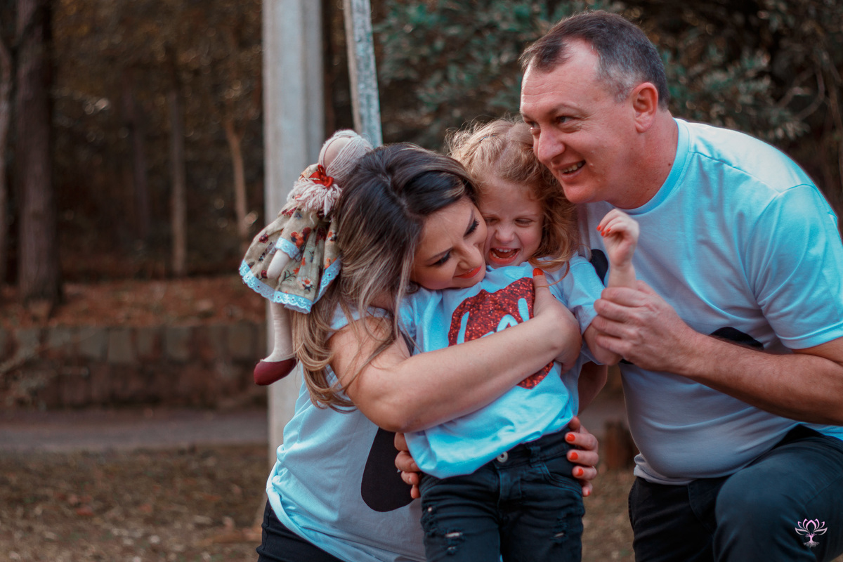 pai e mãe abraçando a filha