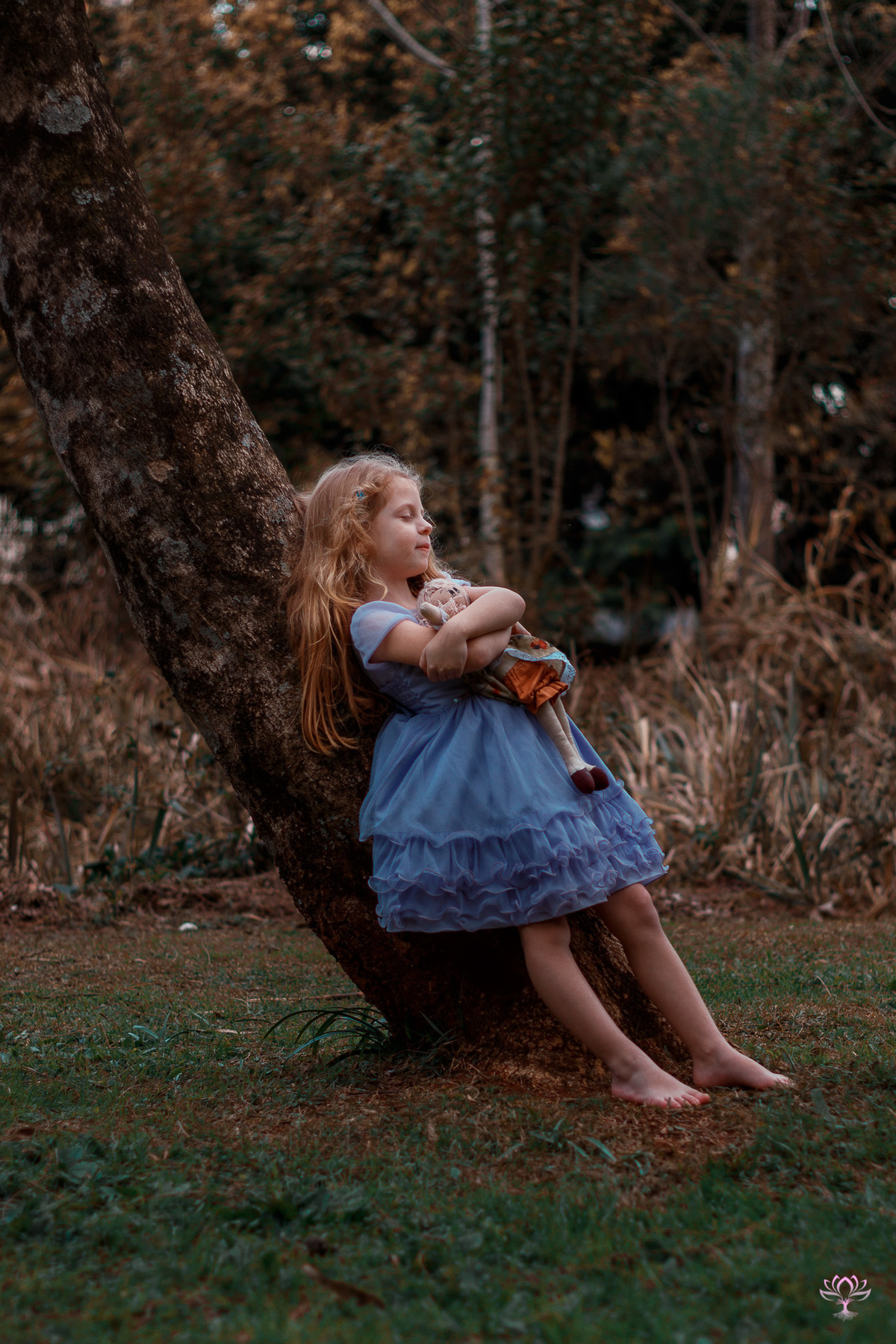 menina encostada na arvore de olhos fechados e abraçada na boneca