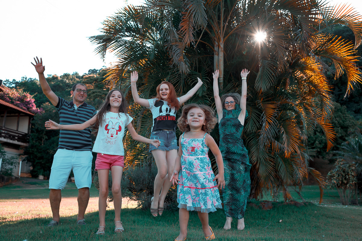 familia pulando com sol no meio das arvores
