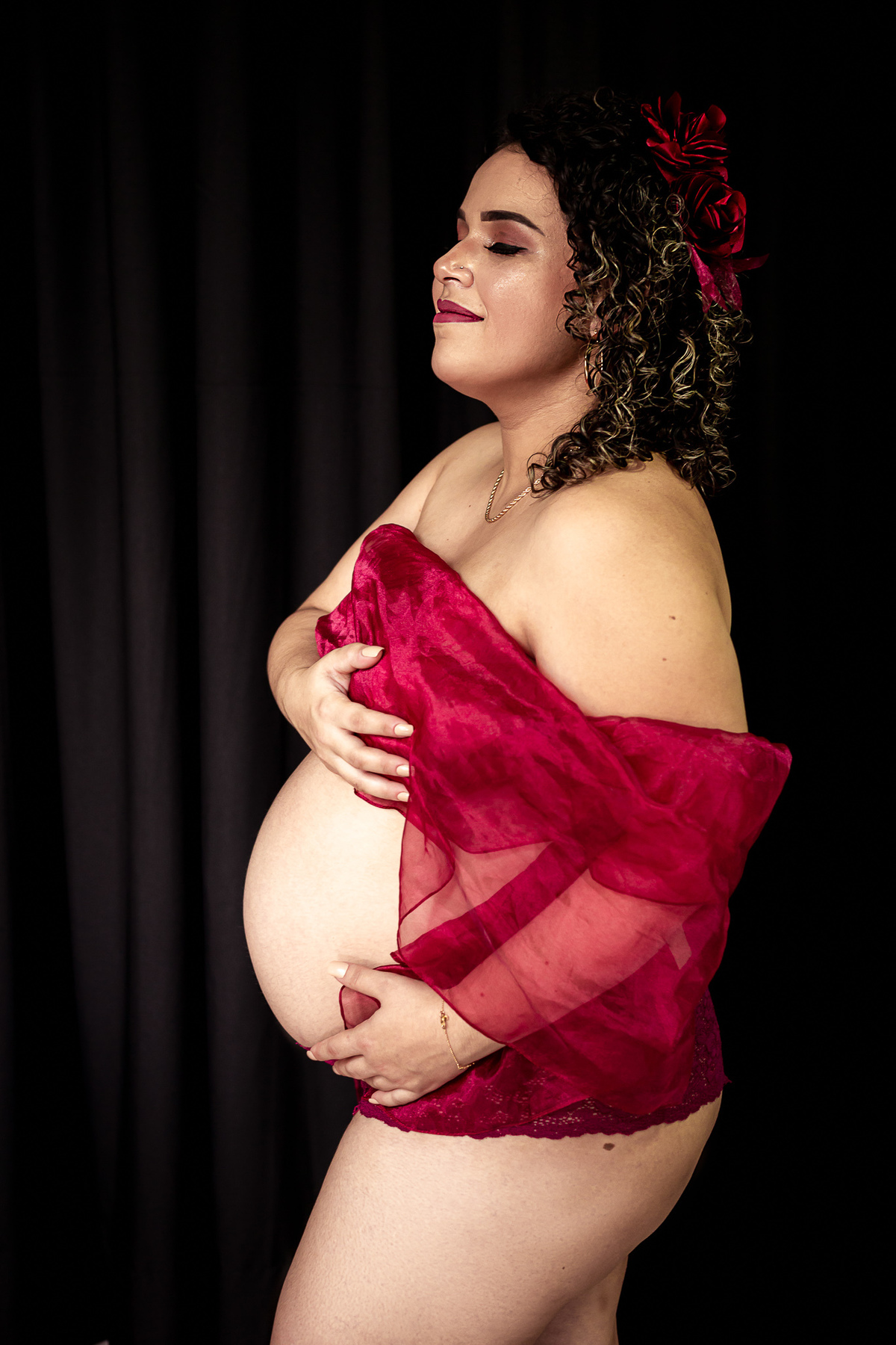 gestante posando em foto de estudio usando apenas um lenço vermelho