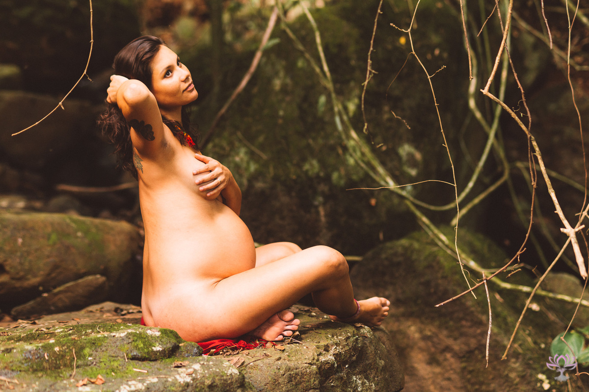 gestante nu sentada em uma pedra