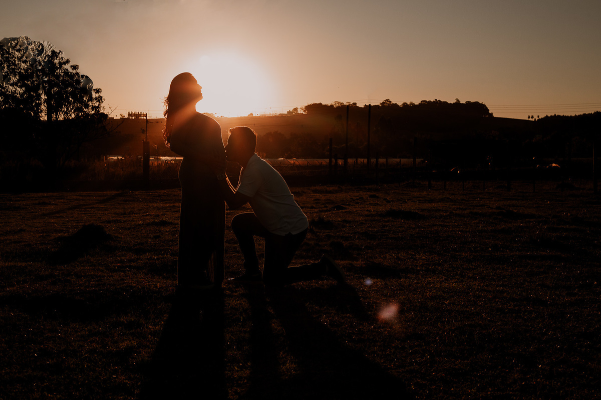 pai beijando a barriga da gravida, luz do por do sol