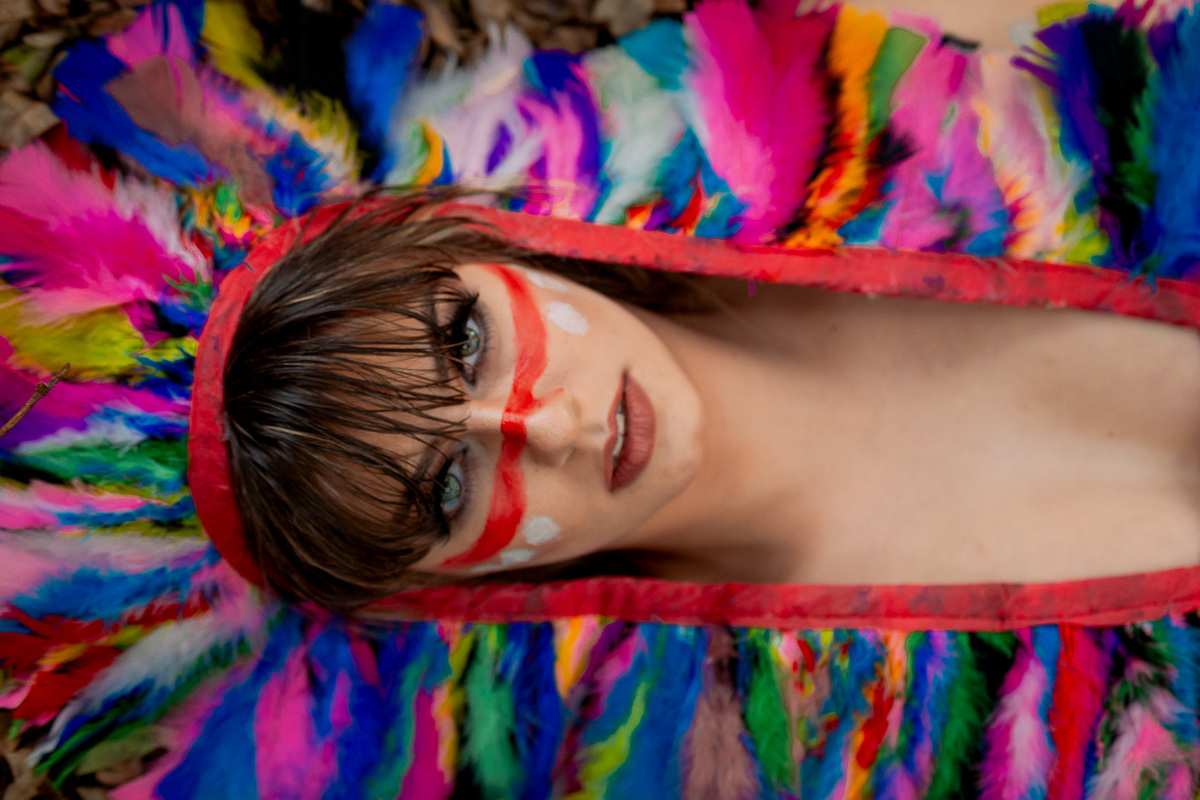 foto tirada de cima modelo deitada com cocar de india