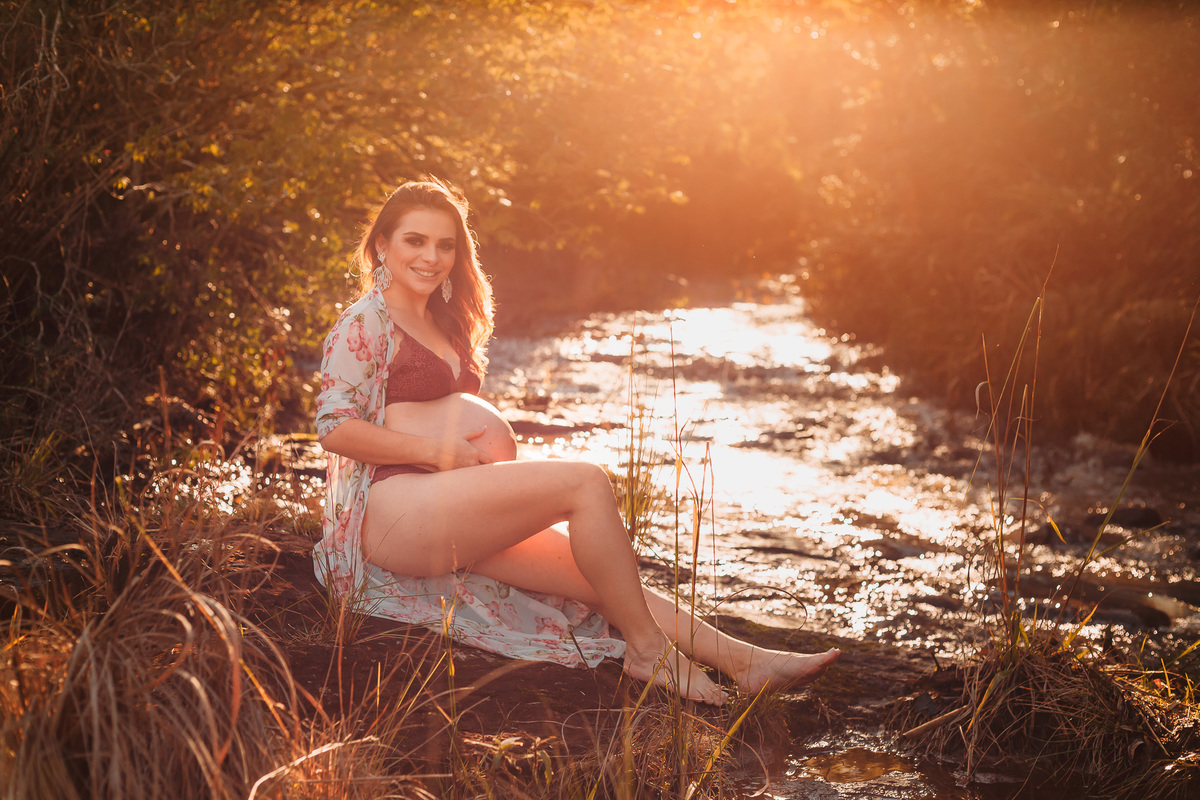 gestante sentada na beira do riacho com flare
