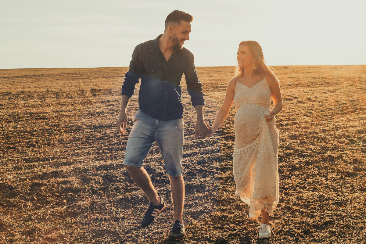 casal de gestante andando no meio da plantação