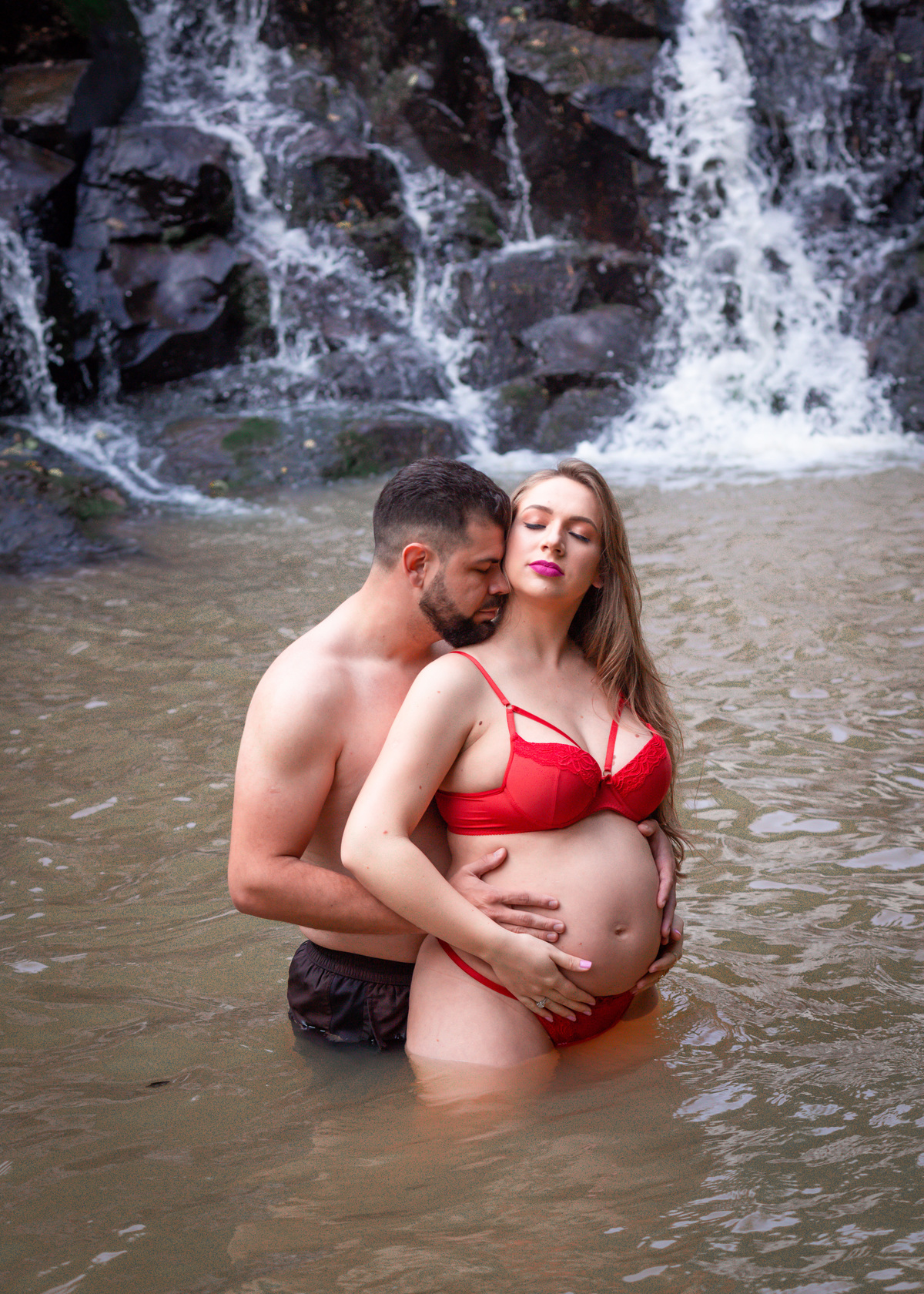 casal de gestante dentro da água, ele cheira o pescoço dela

