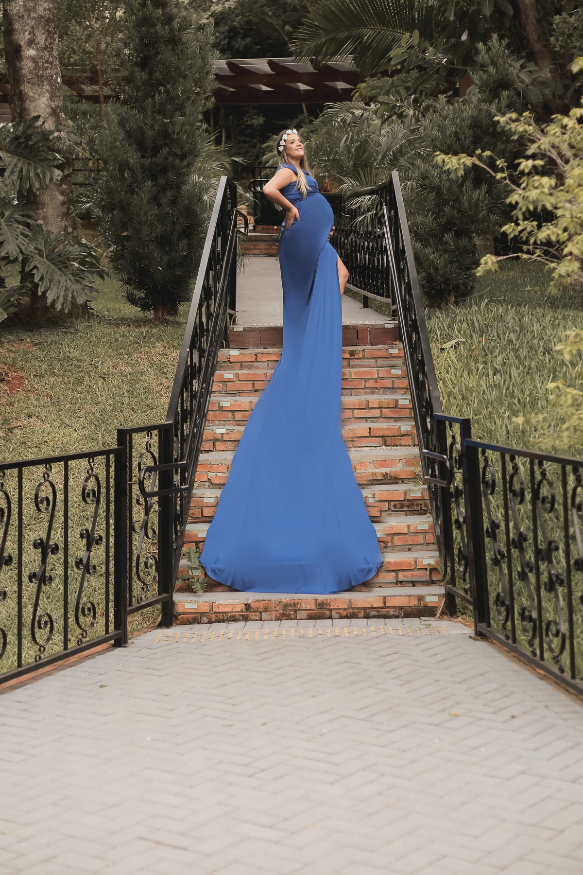 gestante com vestido azul de cauda longa na escada

