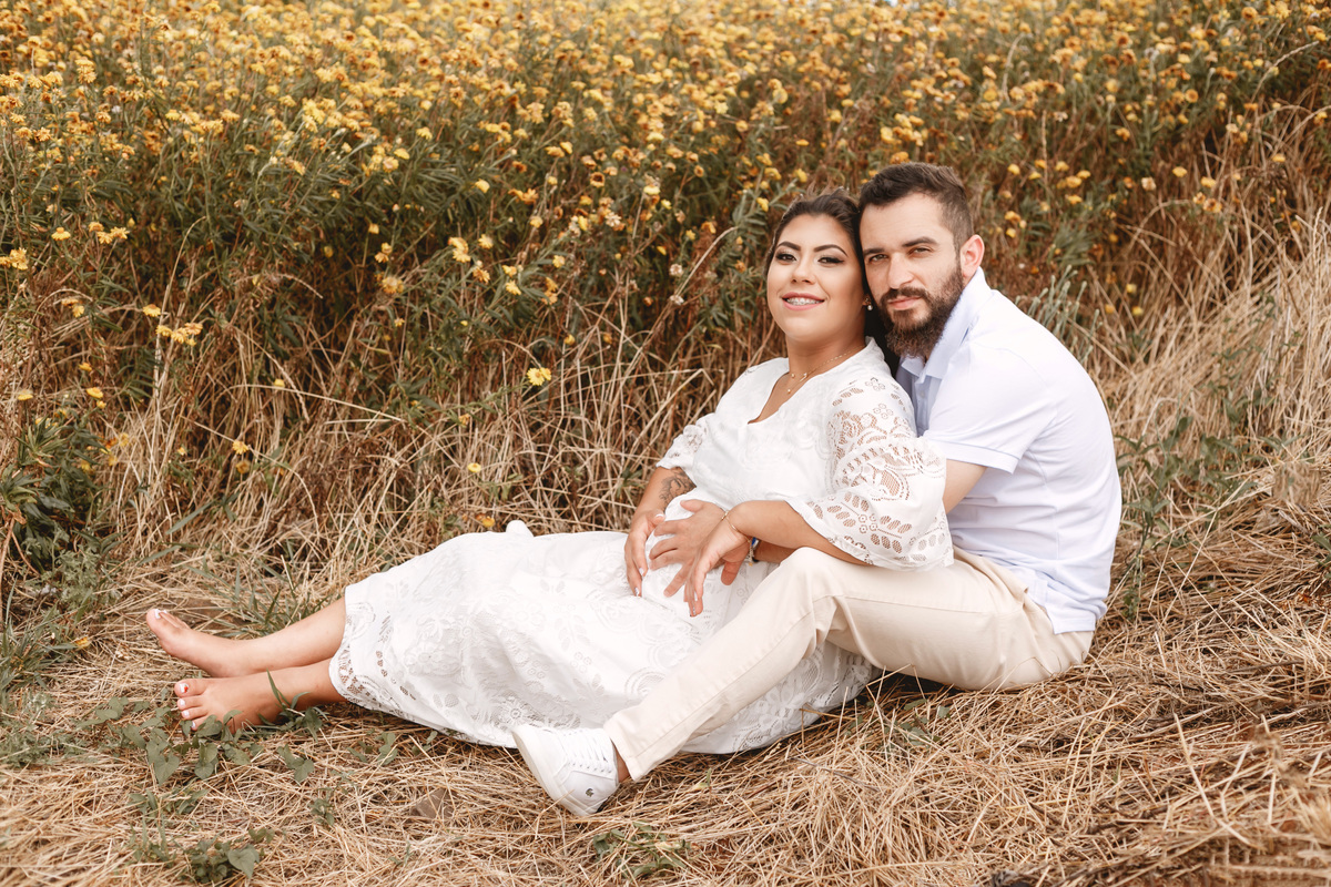 casal sentado frente a um campo de flores amarelas