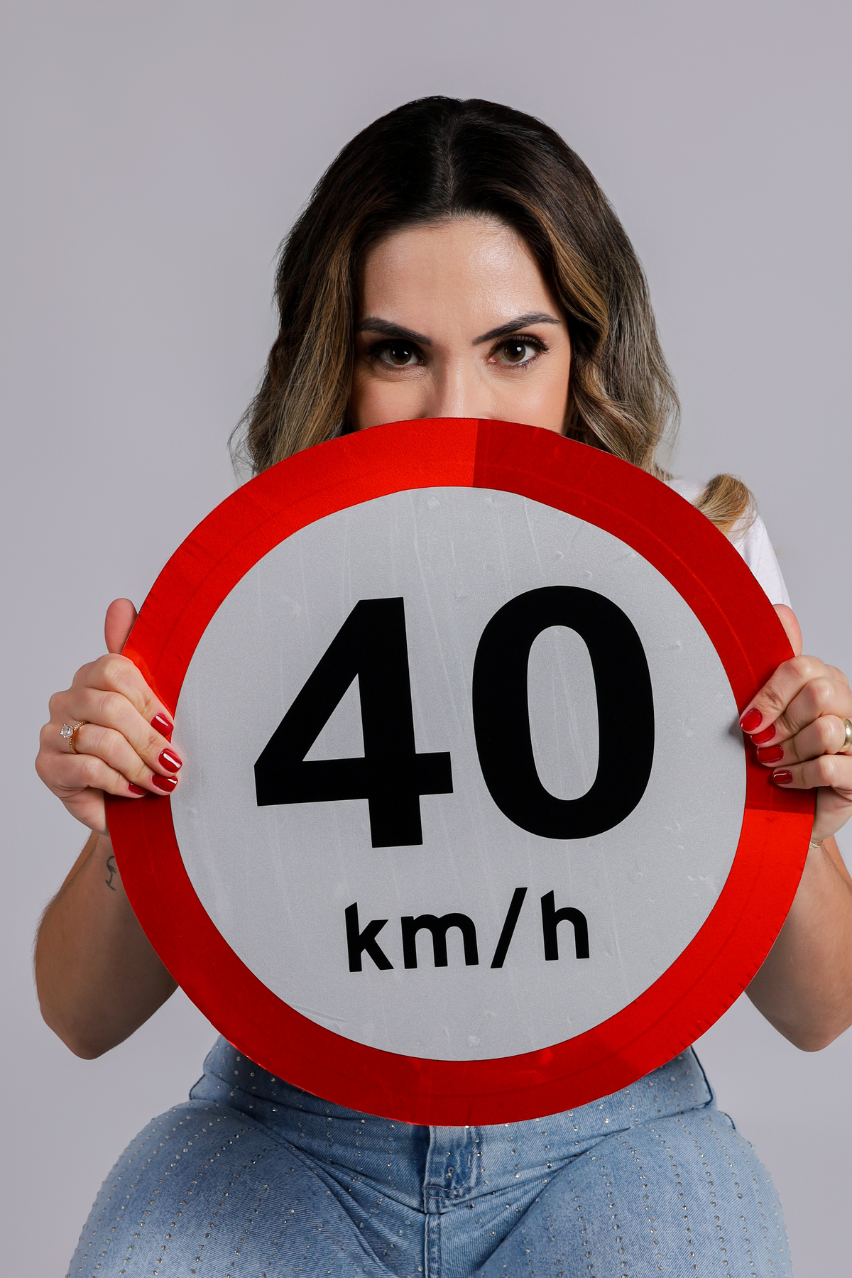 aniversáriante com placa e  com pirulito de coração e chapéu no seu ensaio de aniversário de 40 anos