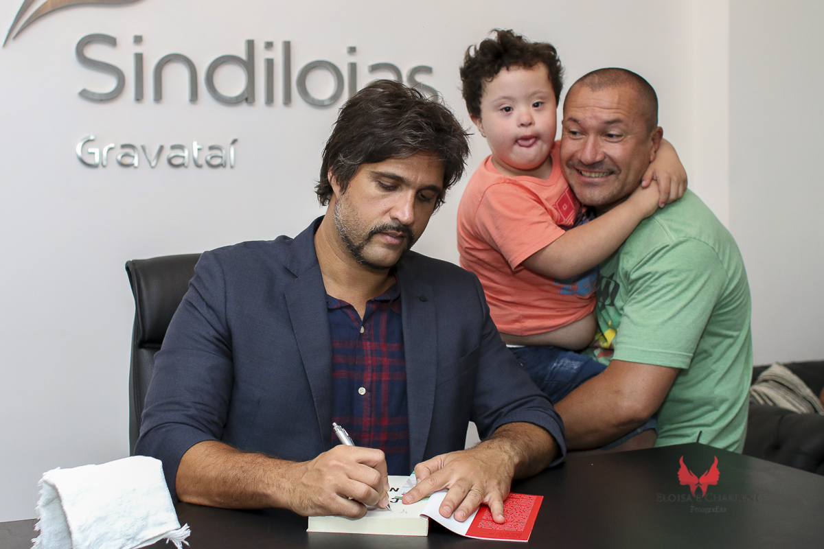 Léo  Chaves assinatura do seu livro, Sindilojas Gravataí, fãs, admiração, palestra, musica, historia de vida, síndrome de down