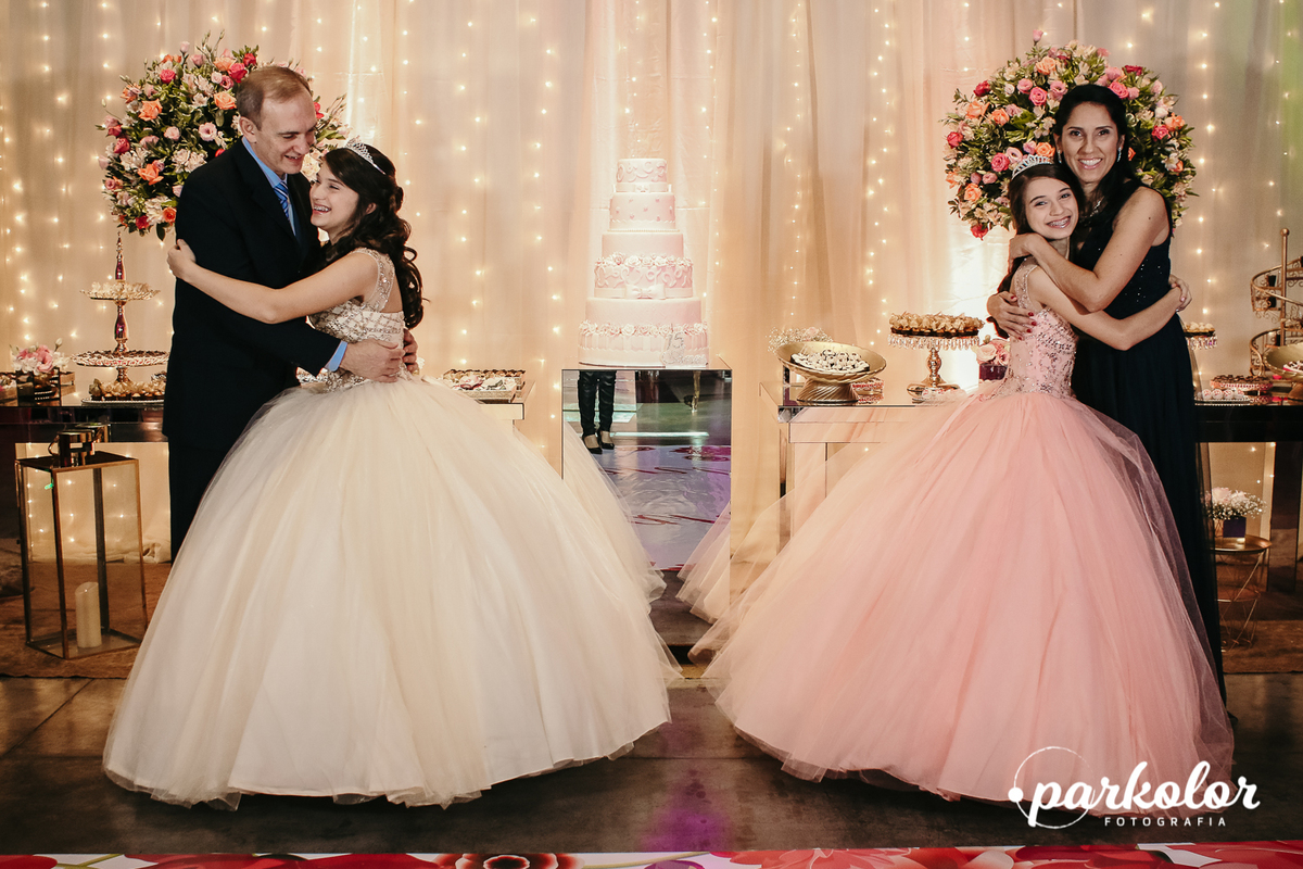 Fotografia da família com abraço e beijo na debutante com vestidos de 15 anos e decoração clássica no salão Rosa dos Ventos