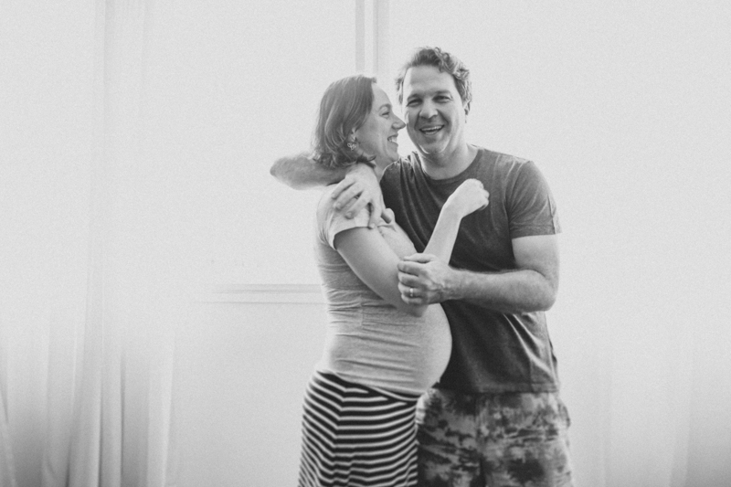 Casal alegre esperando o primeiro filho, foto com luz natural que fizemos no apartamento do casal. Fotografia de família, ensaio gestante, fotos de grávidas. Moyra e Tiago fotografia de família em São Paulo - SP