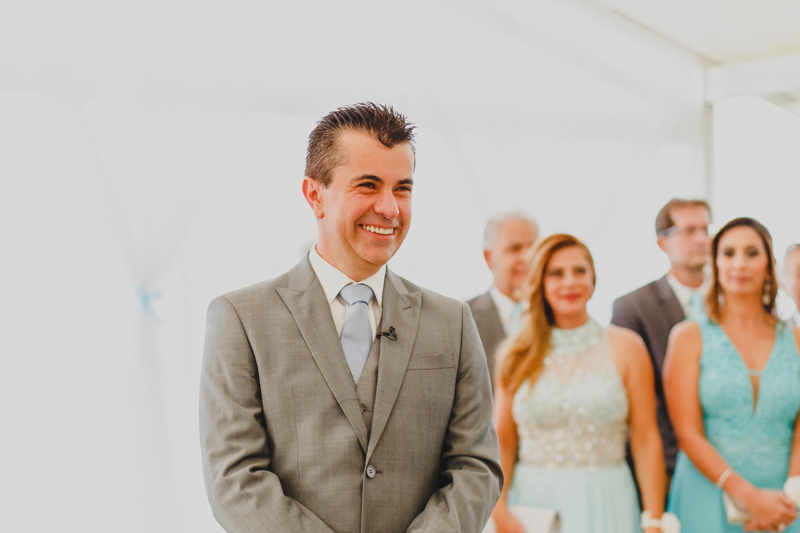 Quando a noiva entrou pelo corredor o noivo ficou bastante sorridente. A expressão do noivo revela toda a emoção desse momento. Fotografia de casamento, fotos de casamento, noiva pó de arroz, vestido de noiva , vestida de branc