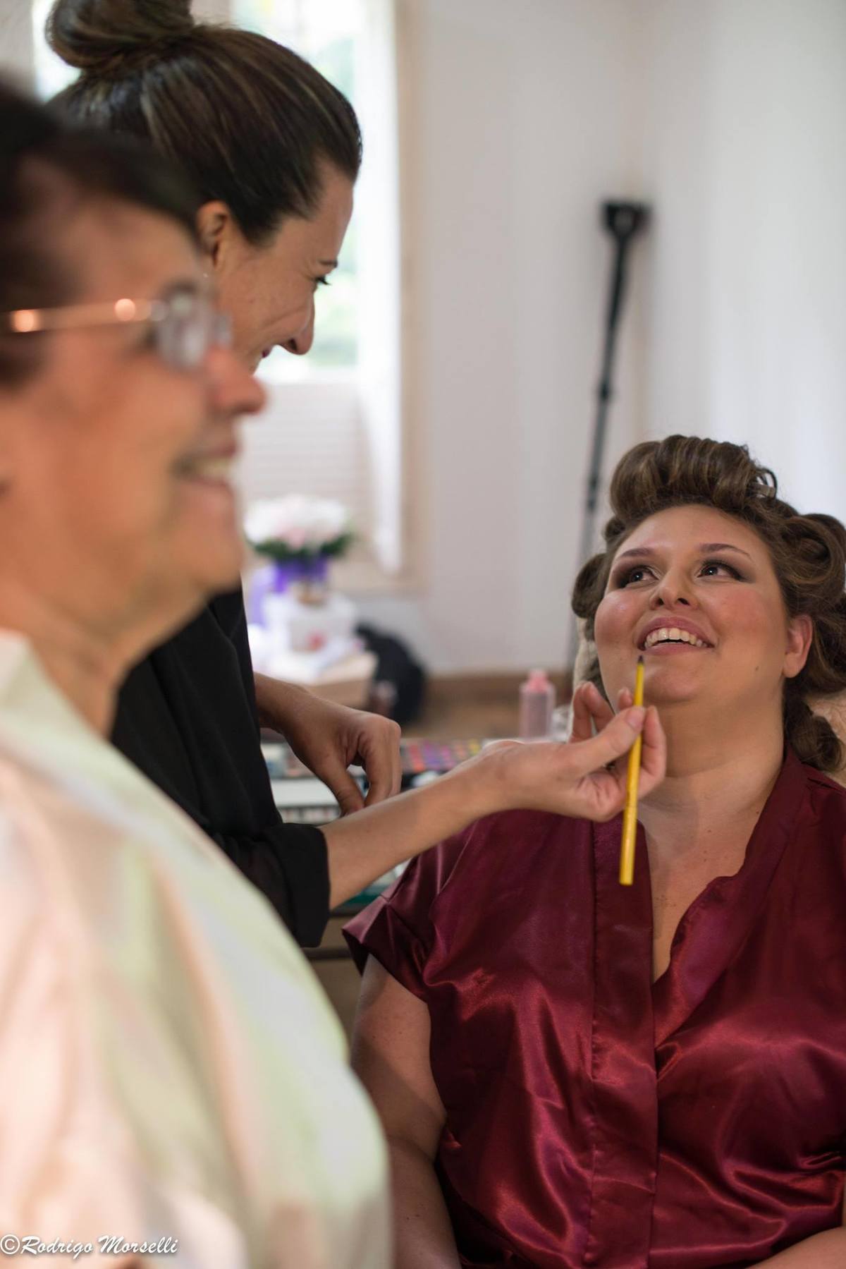 maquiadora trabalhando e sorrindo pra noiva