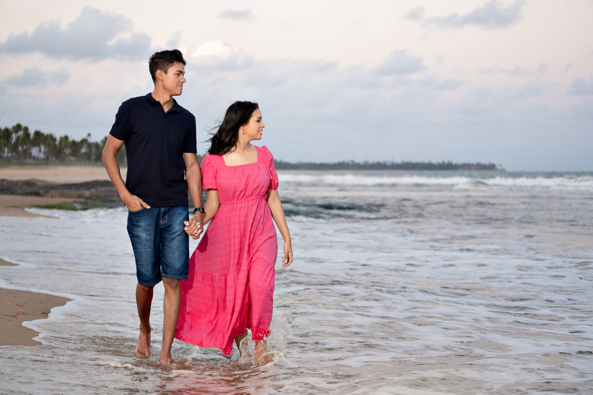 Casal caminhando com água do mar nos pés em Itacimirim - Ensaio pré wedding