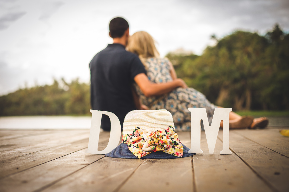 Fotografia de casal, ensaio pré-casamento, casal sentado no pier, cás, abraçados olhando o lago no Parque de Pituaçu, Salvador - BA