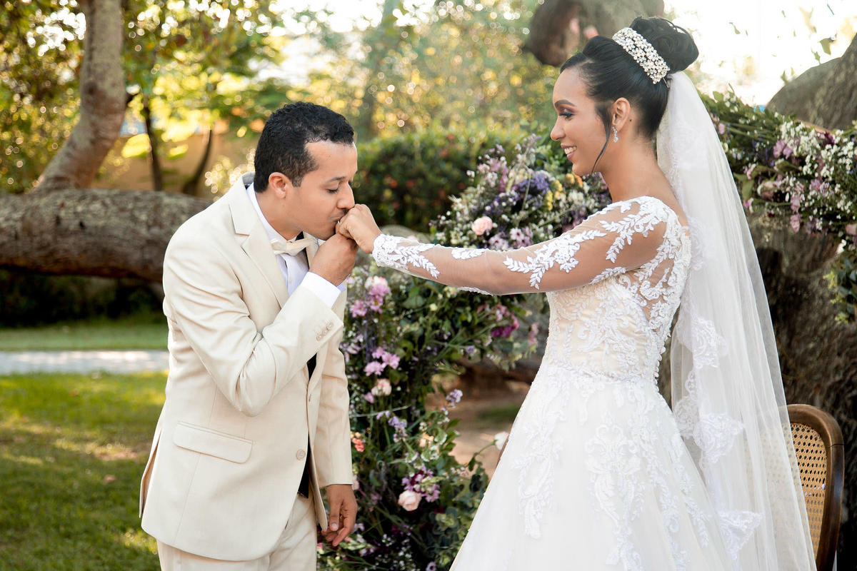 Noiva e noivo trocando alianças ao fundo no Sítio Canto Verde, casal no casamento Lauro de Freitas.