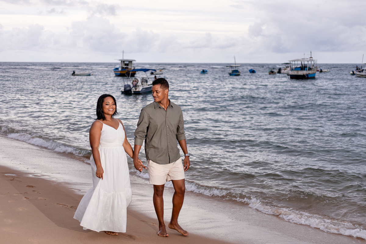 ensaio pré-casamento caminhando praia Bahia, fotografia casal beira mar Salvador, ensaio pré-nupcial movimento natural praia, fotografo casamento caminhada praia Bahia, fotografia casal pegadas areia Praia do Forte, ensaio espontâneo casal praia Salvador,