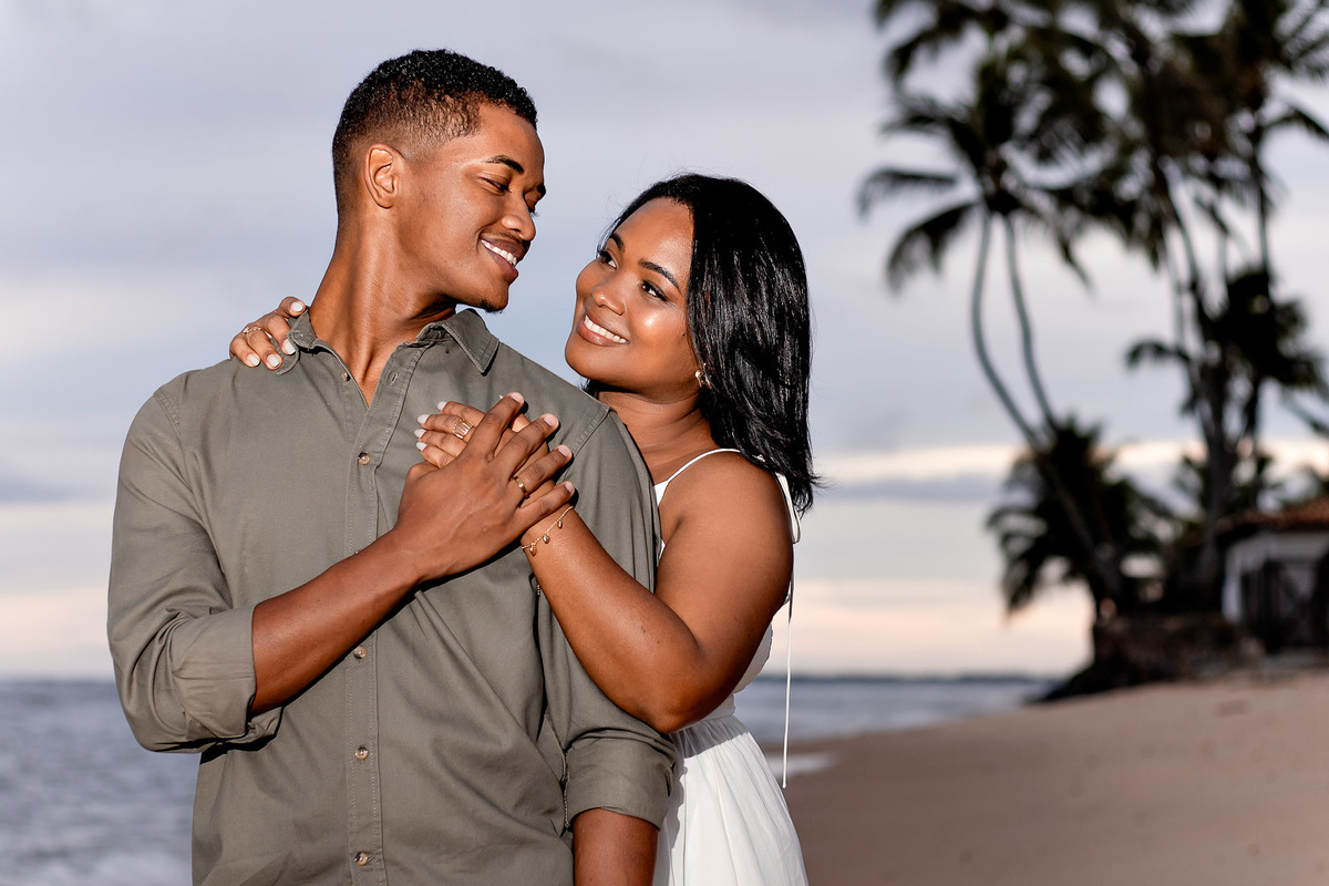 ensaio pré-casamento sorriso casal Bahia, fotografia close entardecer praia Salvador, ensaio pré-nupcial luz dourada Praia do Forte, fotografo casamento golden hour Bahia, close casal feliz praia Bahia, fotografia entardecer noivos Salvador, ensaio casal 
