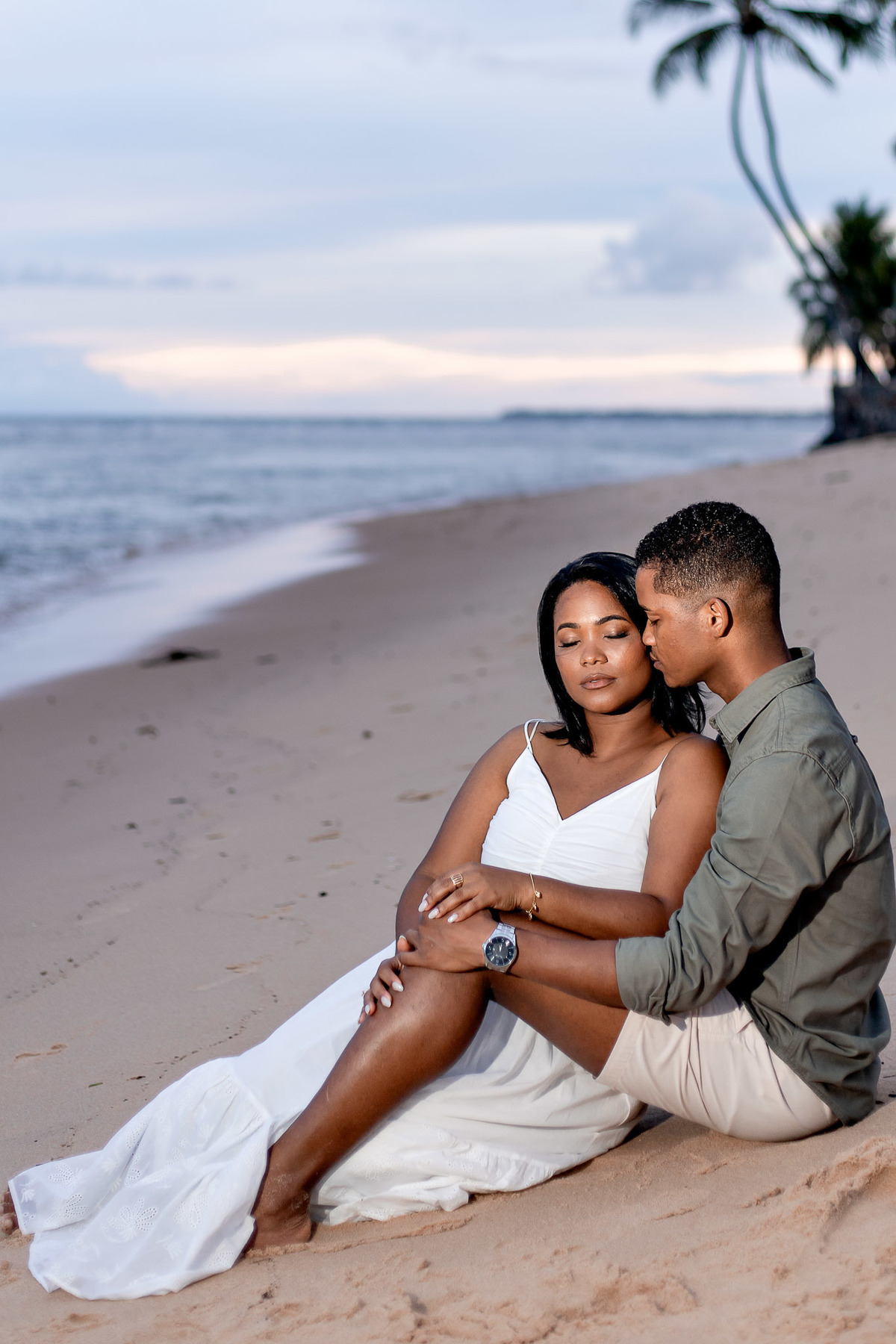 ensaio pré-casamento casal sentado areia Salvador, fotografia momento íntimo praia Bahia, ensaio pré-nupcial entardecer Praia do Forte, fotografo casamento pose sentado praia, casal sentado areia beijo rosto fotografia Bahia, ensaio noivos momento carinho
