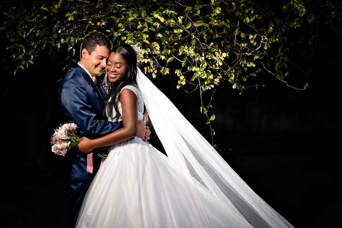 foto noturna casal casamento, casal árvore noite, véu noiva noite, iluminação dramática casamento, fotografia noturna casamento Bahia, casal apaixonado noite