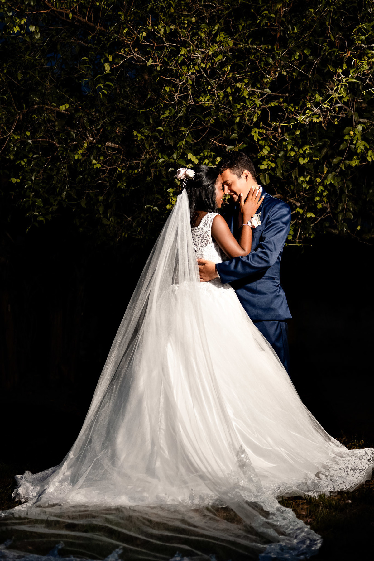 foto noturna casal romântico, véu ao vento noite, iluminação dramática casamento, casal casamento noite, fotografia noturna casamento Conceição do Jacuípe, véu longo noiva