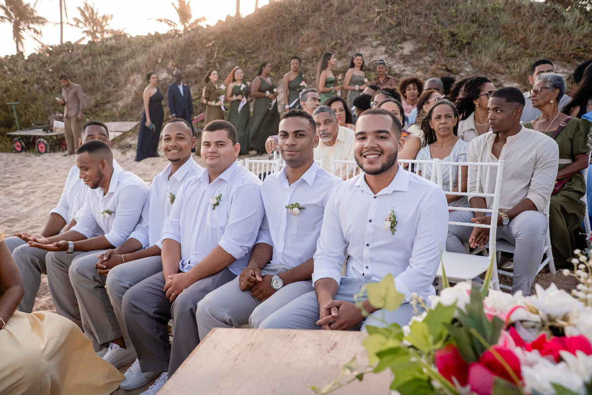 Padrinhos sentados na areia durante casamento na Praia do Flamengo, Salvador